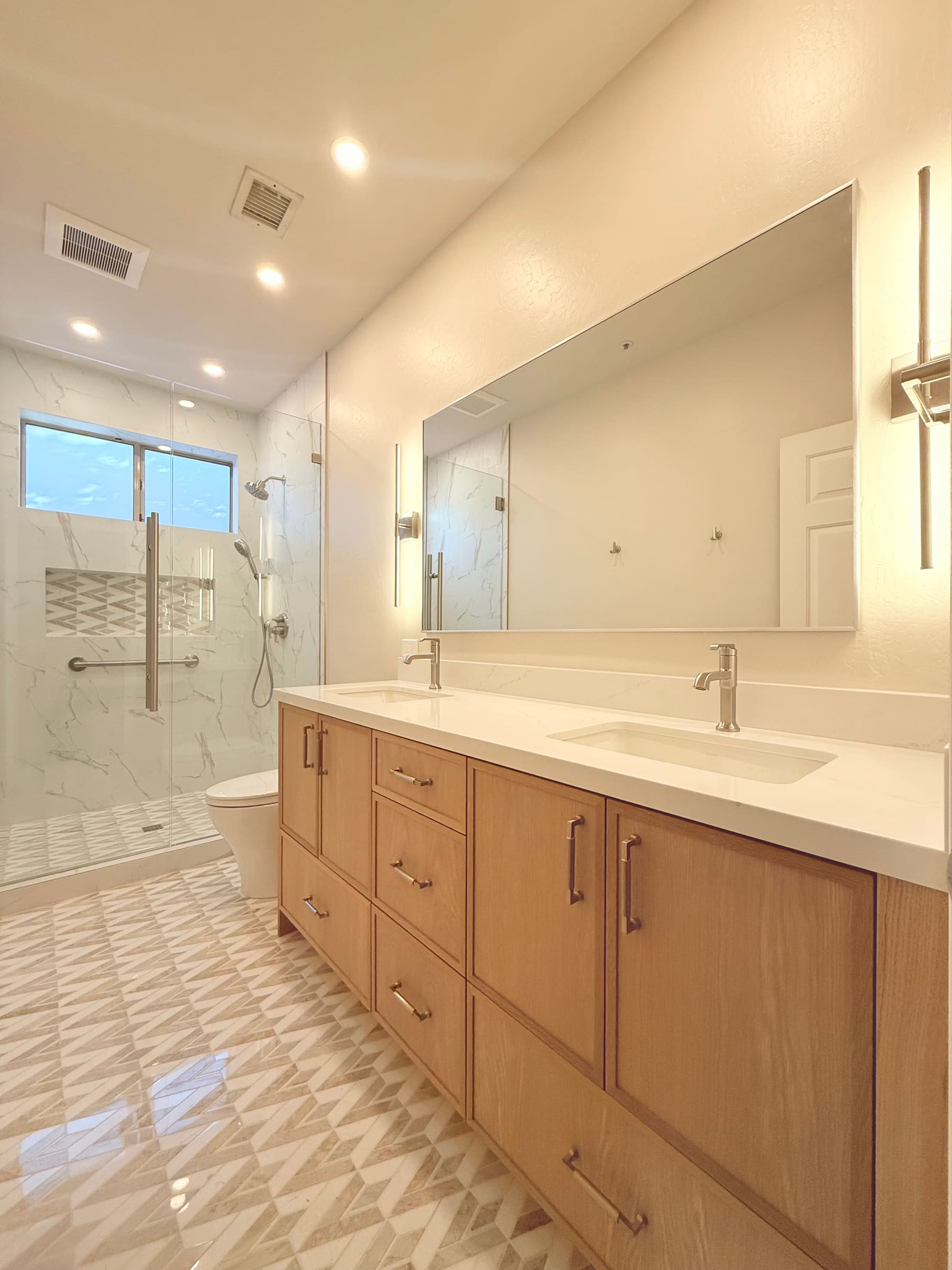 White oak double vanity with quartz top and chevron tile floor — Phoenix custom cabinetry