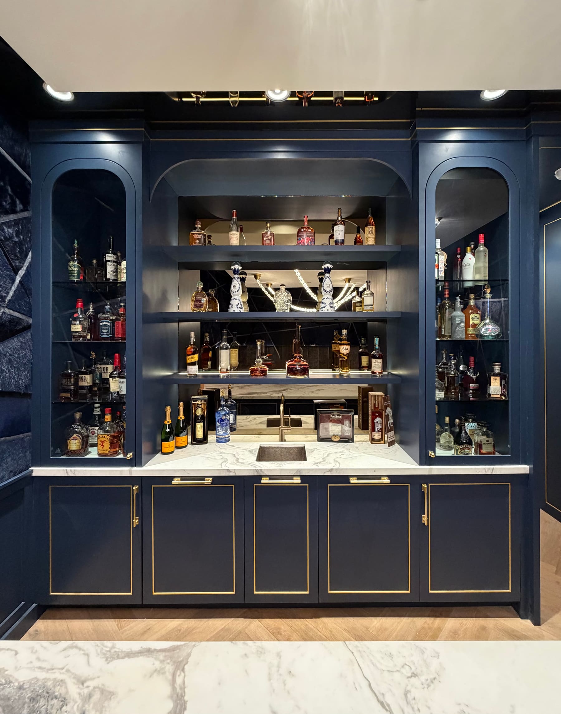 Navy painted home bar built-in with brass trim and lighted display uppers — Phoenix custom cabinetry