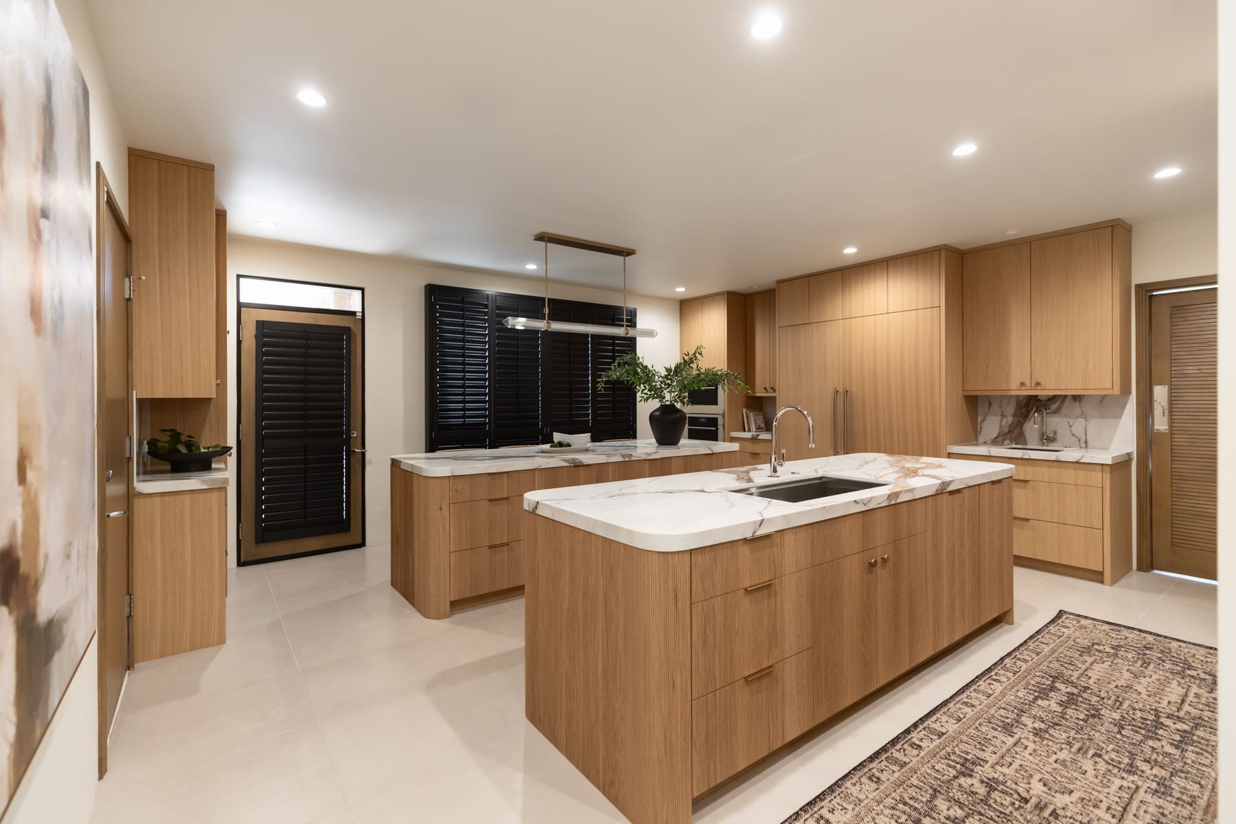White oak kitchen with double islands, reeded fronts, and marble counters — Phoenix custom cabinetry